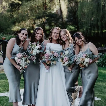 A bride with her bridesmaids in sage green dresses
