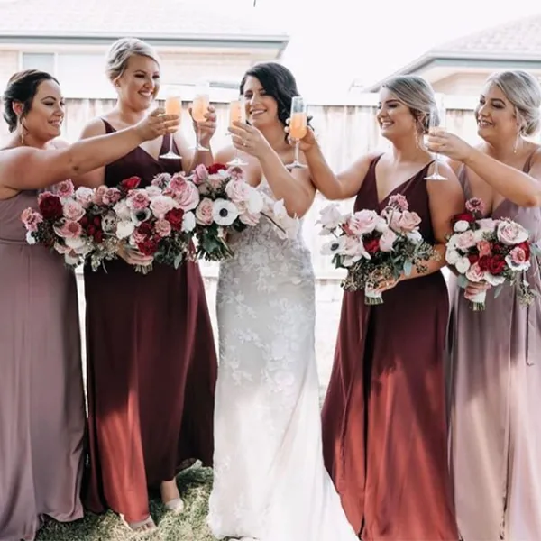 Bridesmaids in rich red dresses raising a toast with the bride