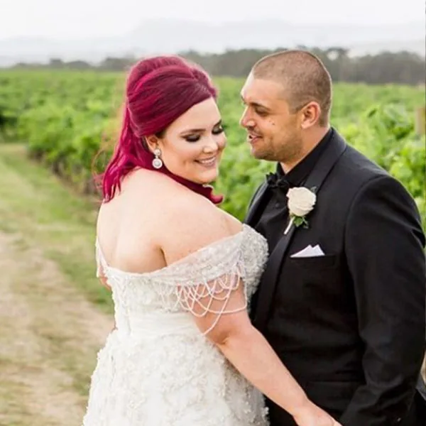A bride with bright pink hair and her groom in a vineyard